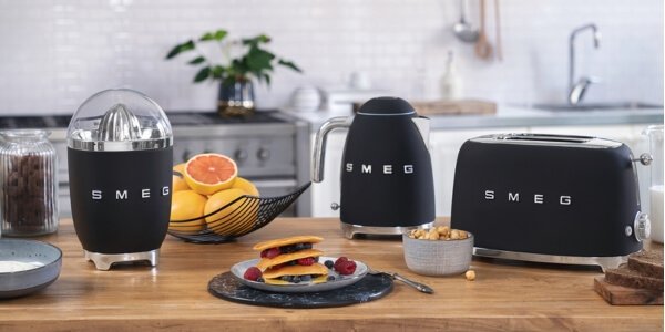 Black Smeg citrus juicer, kettle and toaster on a kitchen worktop