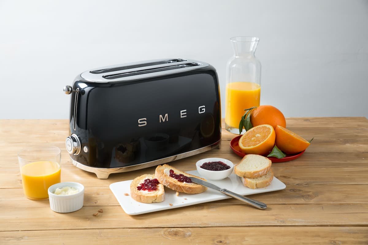 torradeira retro smeg ao lado de alimentos e sucos