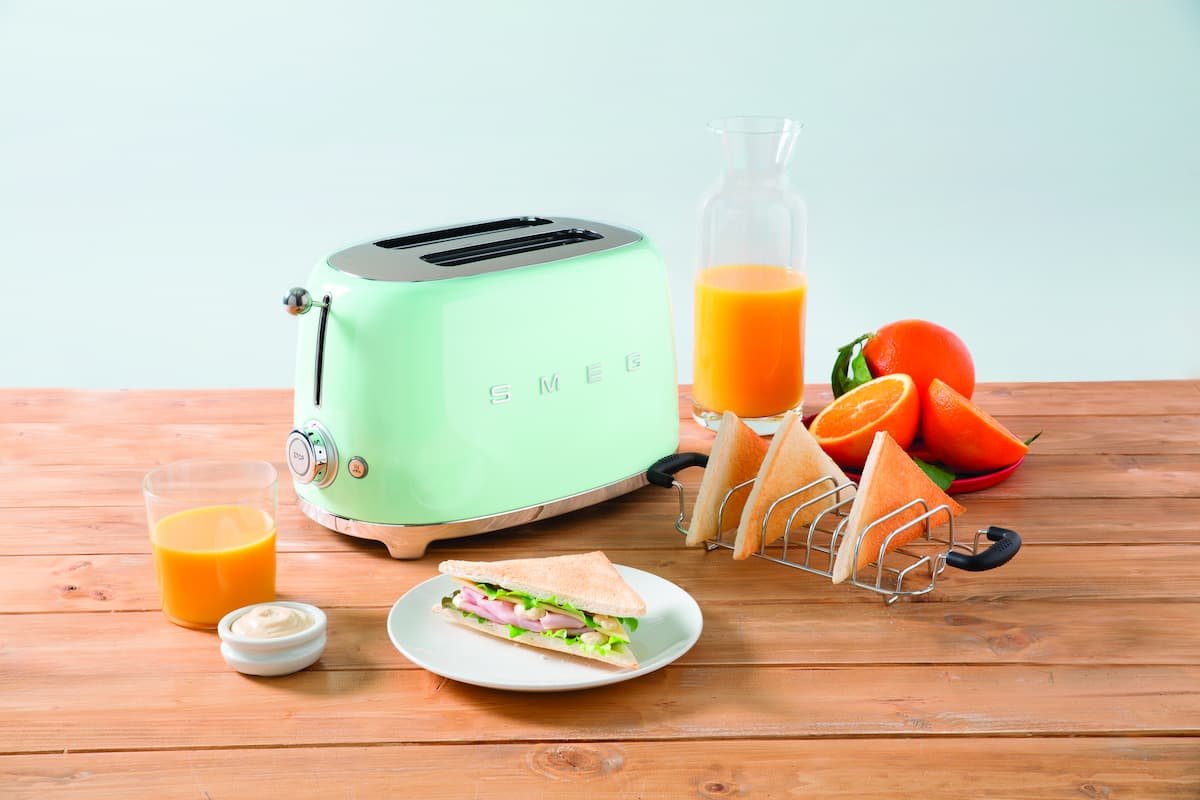 torradeira verde smeg em bancada ao lado de sucos e alimentos